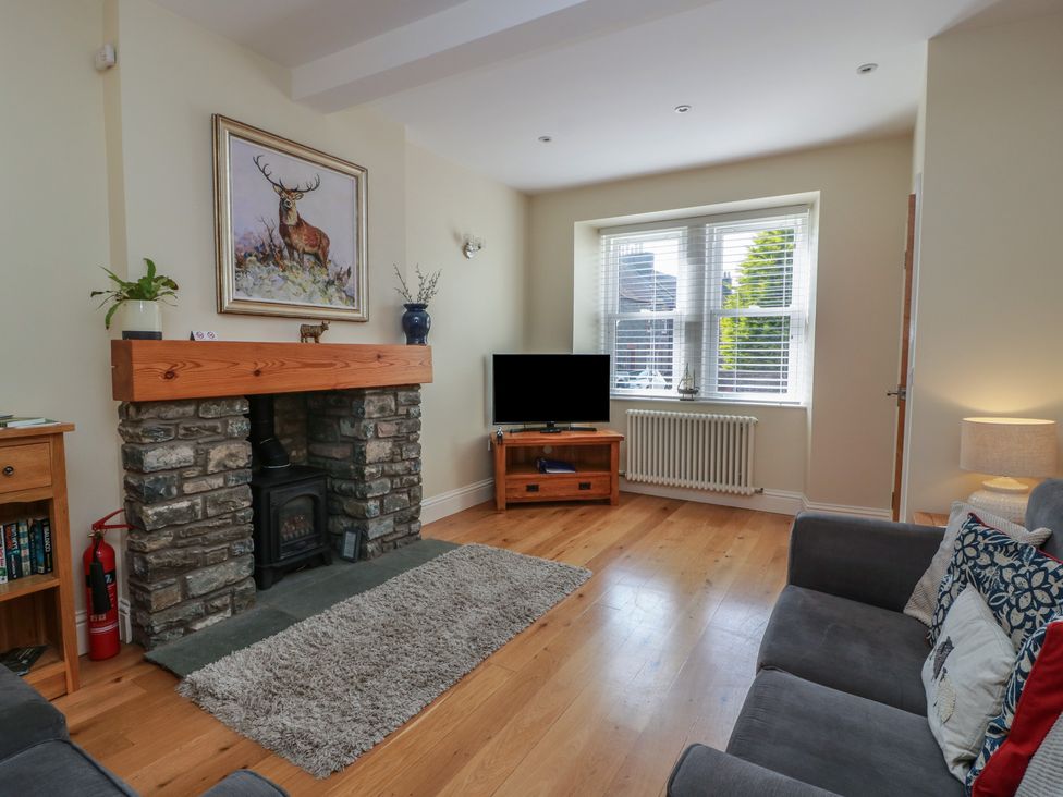 A living room with a fireplace and television at Haven Cottage in Kirkcudbright
