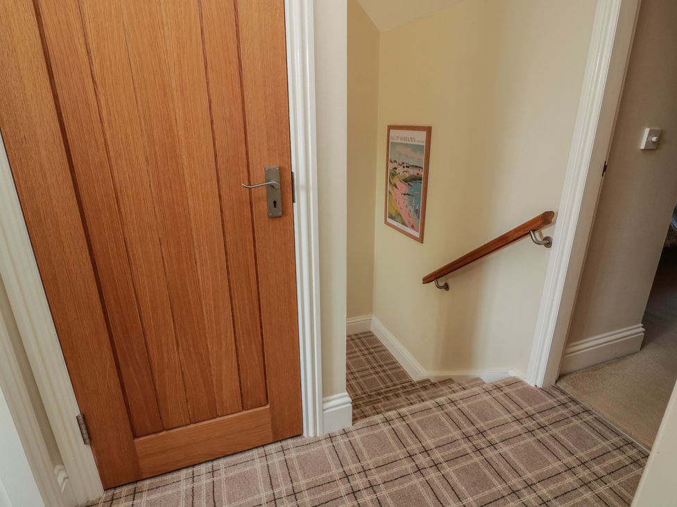 A staircase with a wooden door and handrail at Haven Cottage in Kirkcudbright
