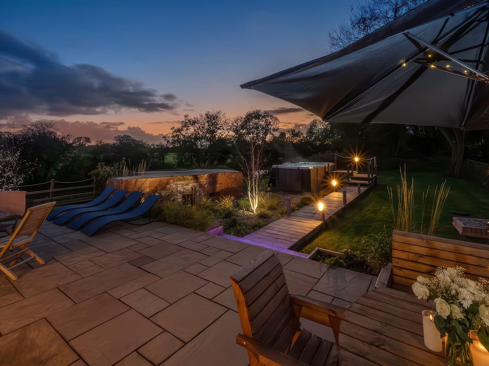 A garden with a patio, hot tub and lounge chairs at Station House in Highbridge