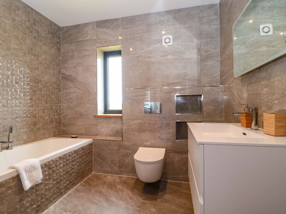 A bathroom with a bathtub, toilet, sink, and window at Station House in Bason Bridge near Highbridge