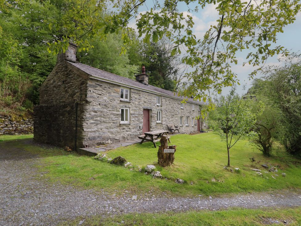 A stone cottage with garden and seating area at The Long House in Penmachno