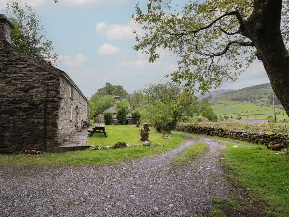 An outdoor scene with a stone building and gravel path at The Long House Penmachno
