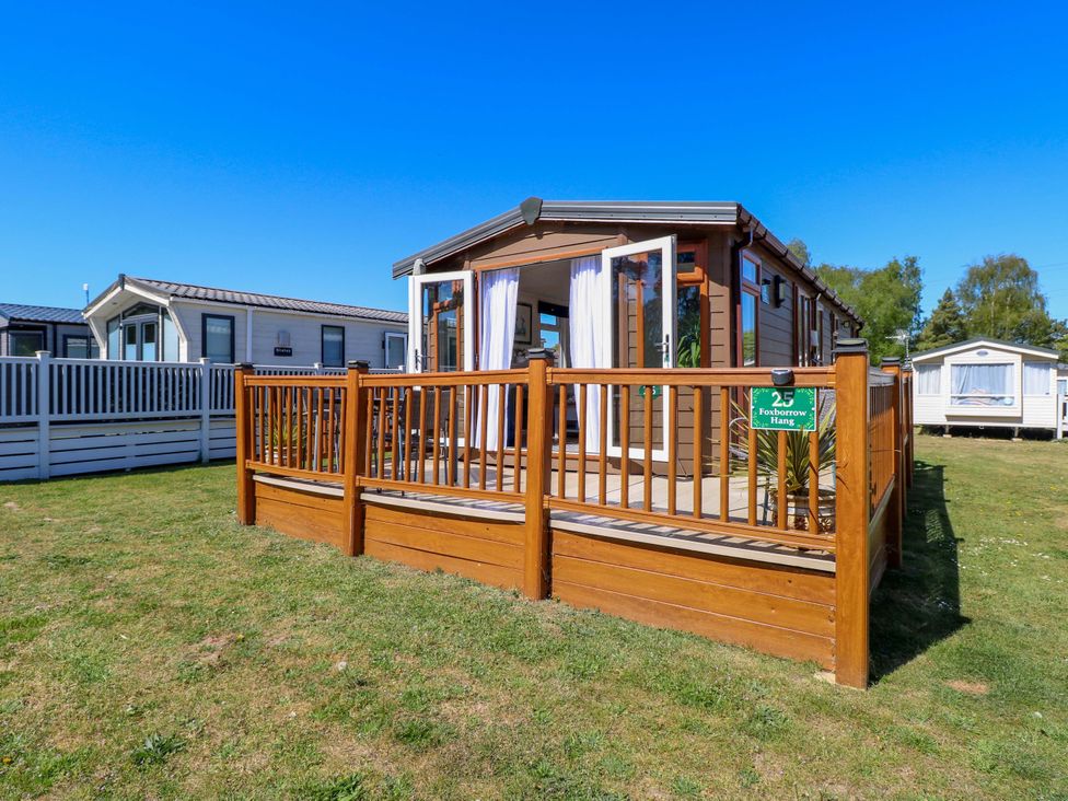 A caravan with a wooden deck and sign at 25 Foxburrow Hang in Fritton near Belton