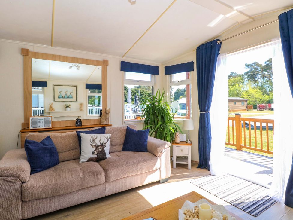 A living room with a sofa, mirror, and plant at 25 Foxburrow Hang in Fritton near Belton