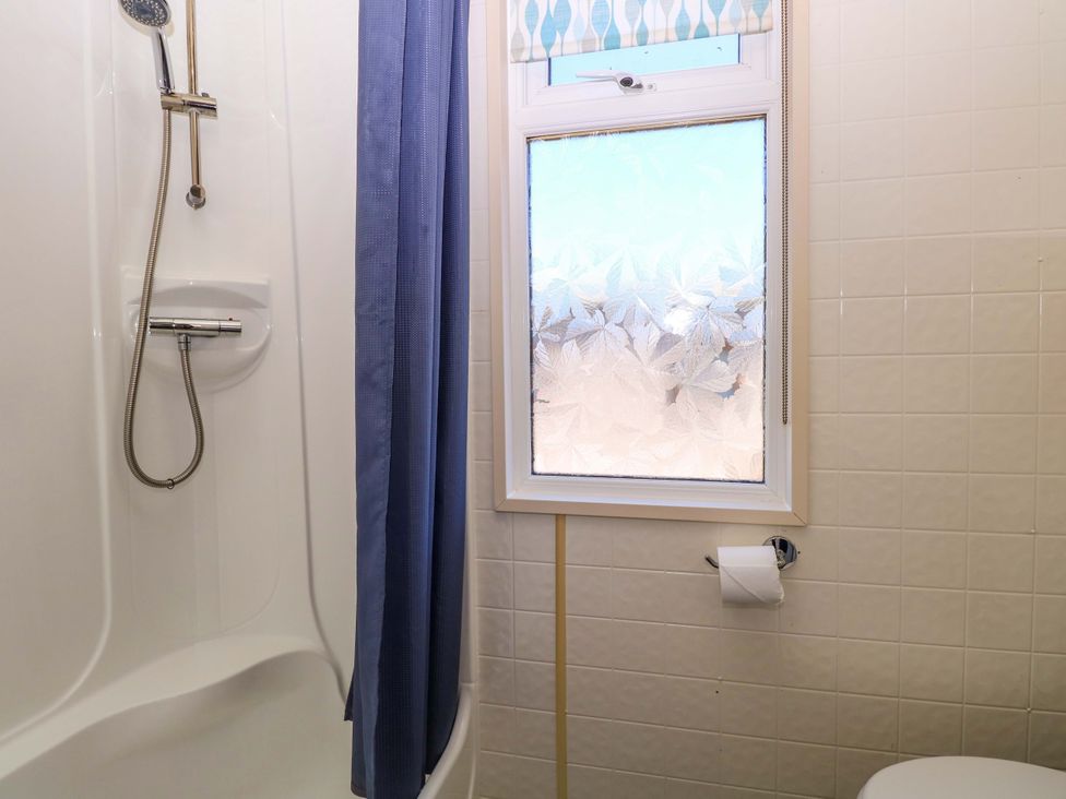 A shower with a curtain and a toilet at 25 Foxburrow Hang in Fritton near Belton