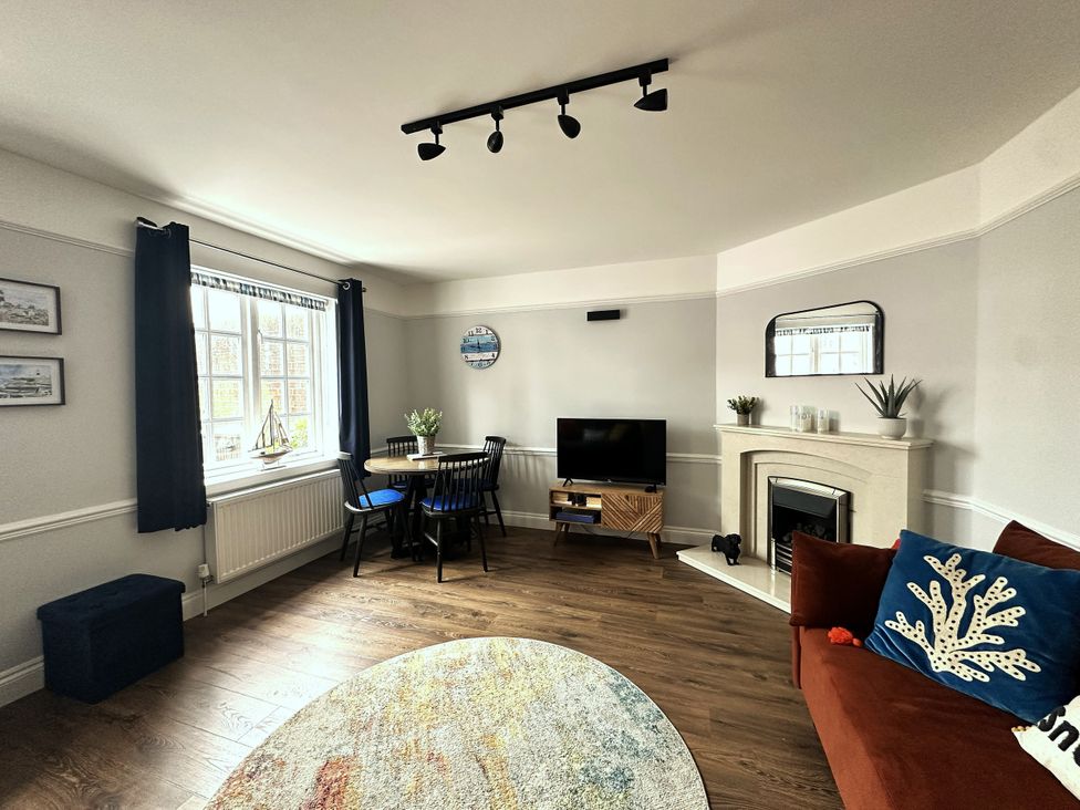 A living room with a table and chairs and a television at Melanie's Cottage in Brewers Quay Harbour