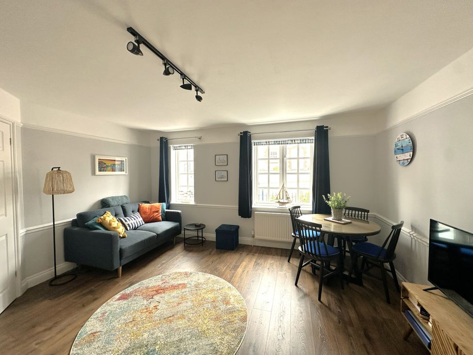 A living room with a sofa and dining table at Melanie's Cottage Brewers Quay Harbour