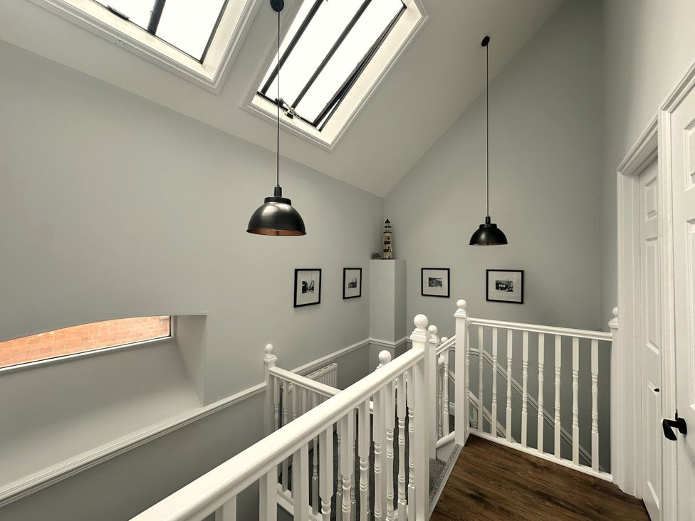 A hallway with photographs on the wall at Melanie's Cottage, Brewers Quay Harbour