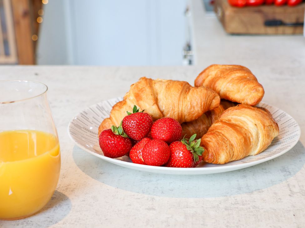 A plate with croissants and strawberries accompanied by a glass of orange juice at Hawthorn Cottage Silpho near Scalby