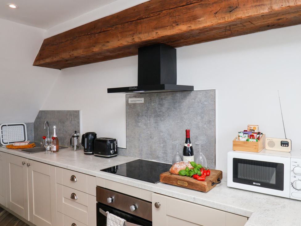 A kitchen with a stove, microwave, and vegetables at Hawthorn Cottage in Silpho near Scalby