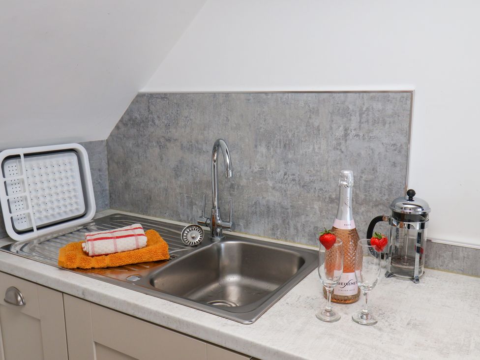 A kitchen with a sink, a champagne bottle, and glasses at Hawthorn Cottage in Silpho near Scalby