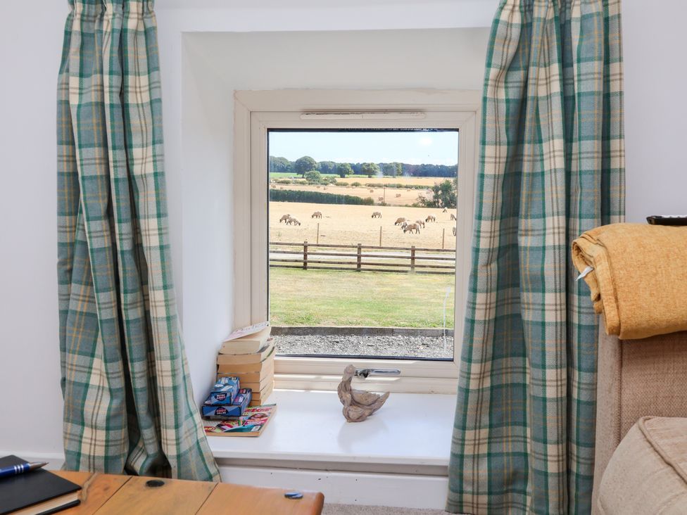 A living room with a window overlooking the field at Hawthorn Cottage in Silpho near Scalby