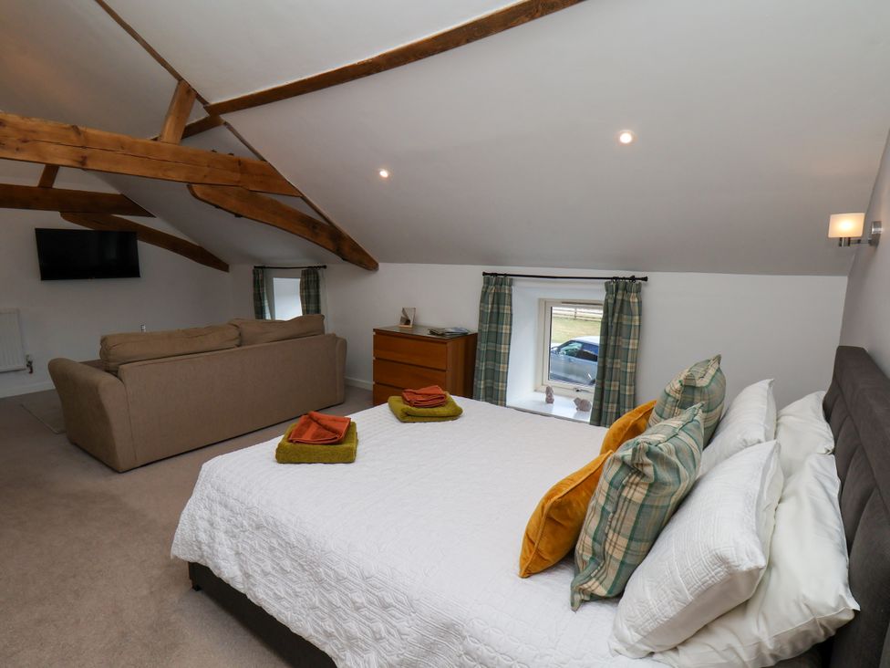 A bedroom with a bed and sofa at Hawthorn Cottage Silpho near Scalby