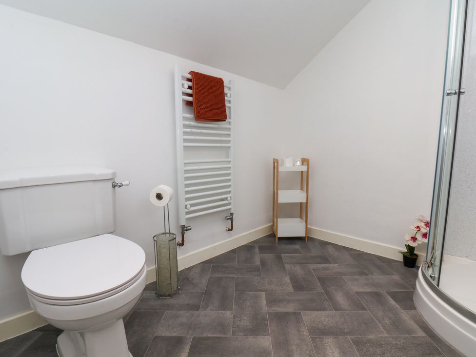 A bathroom with a toilet, towel radiator and shelf at Hawthorn Cottage in Silpho near Scalby