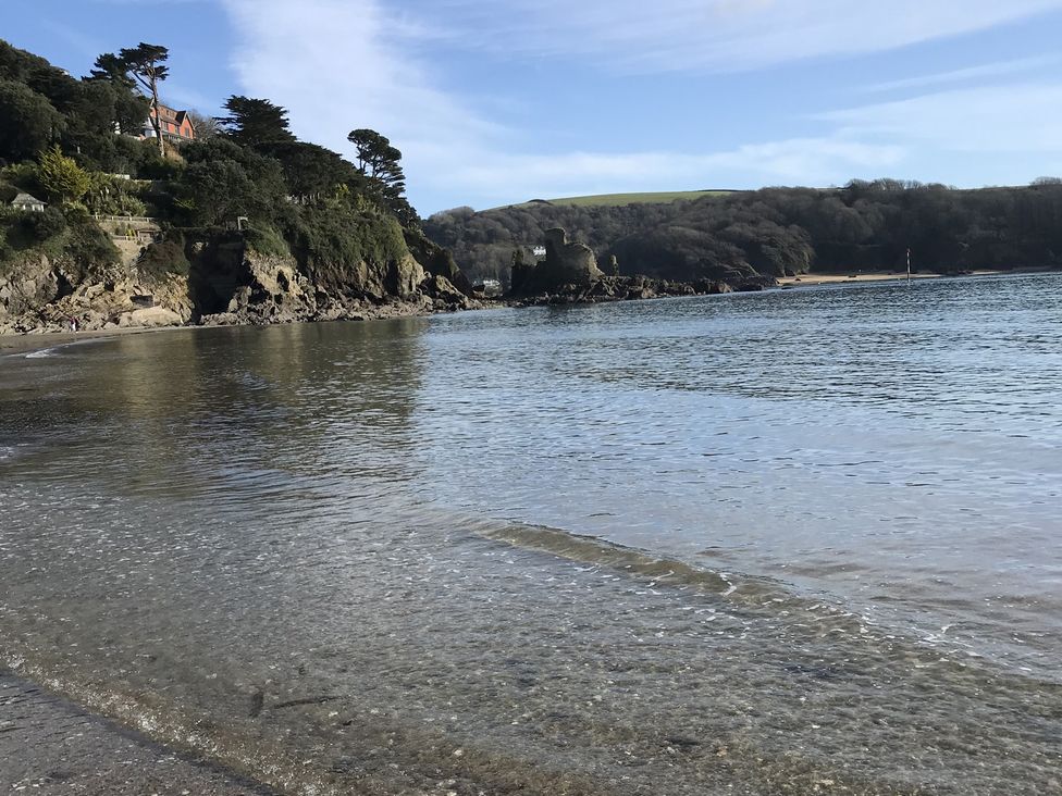 A beach with water and rock formations at Firm Anchor in Salcombe