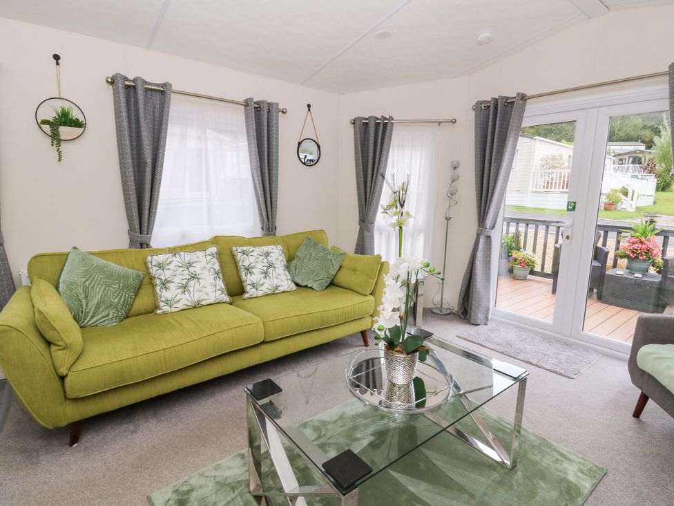 A living room with a green sofa and glass table at The Haven