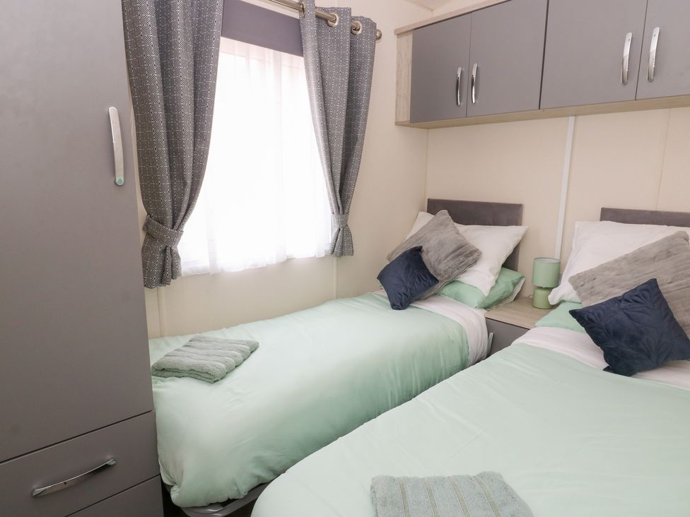 A bedroom with two single beds and grey curtains at The Haven