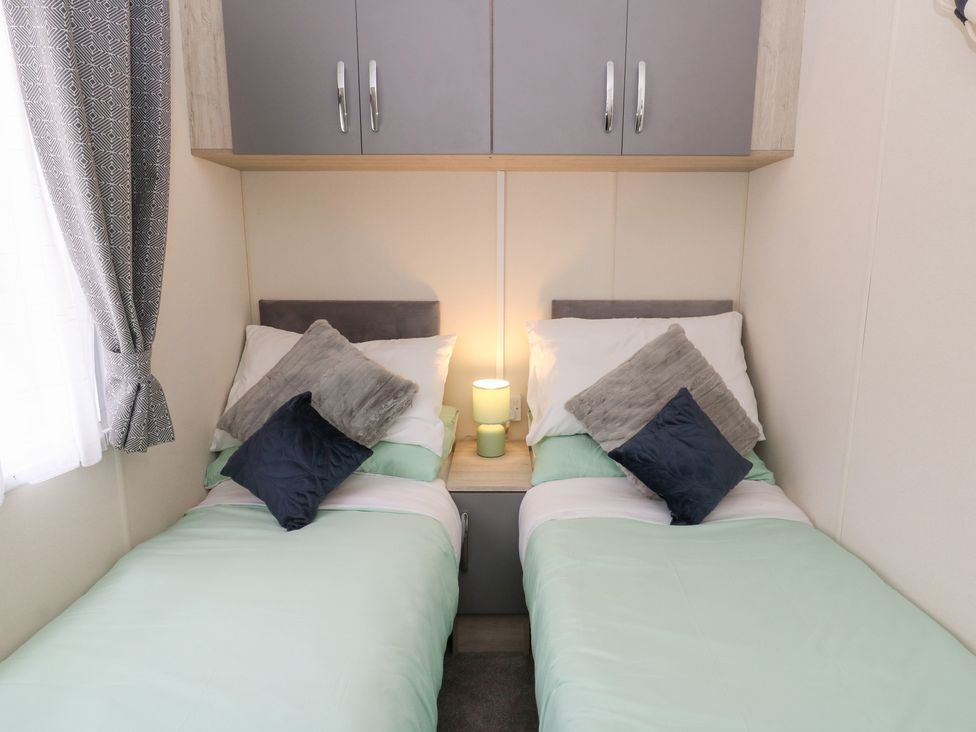 A bedroom with two single beds and a lamp on a shared bedside table at The Haven