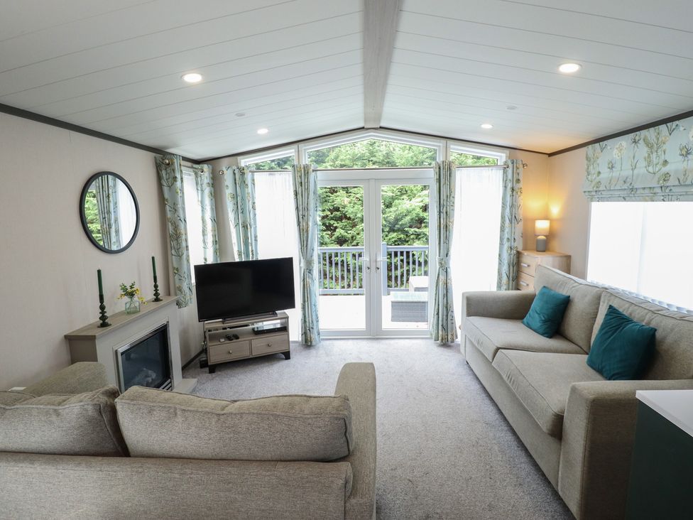 A living room with a sofa, television, and sliding door at Heather William Lodge near Woodhall Spa