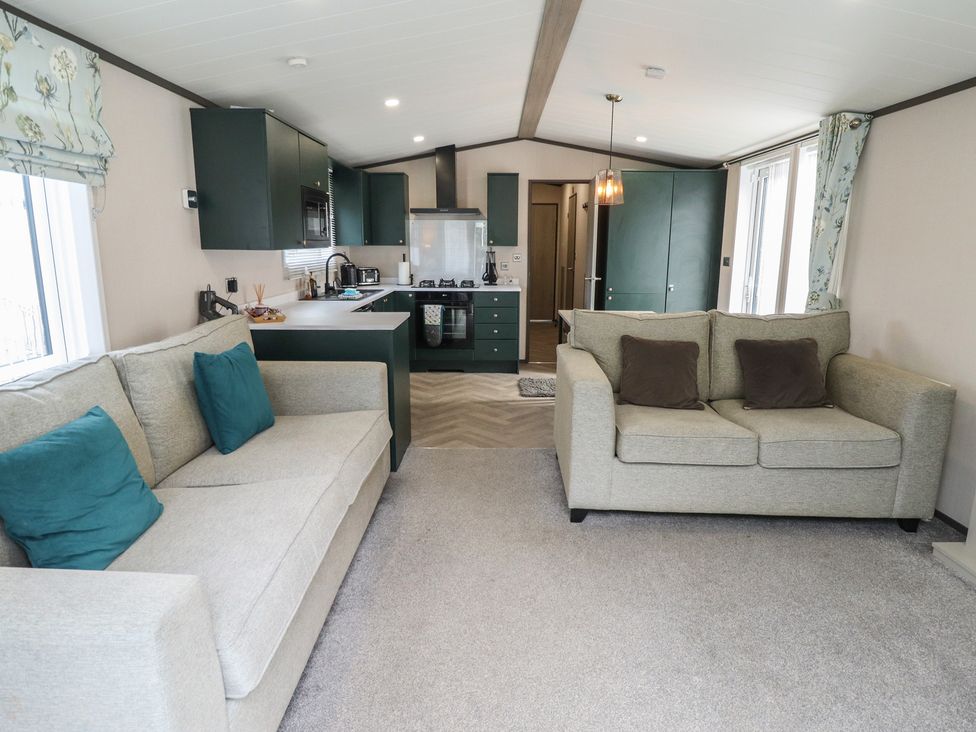 A living room with a sofa and kitchen area at Heather William Lodge near Woodhall Spa