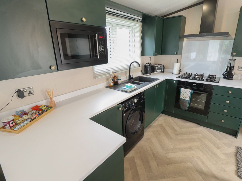 A kitchen with appliances including a stove and washing machine at Heather William Lodge near Woodhall Spa