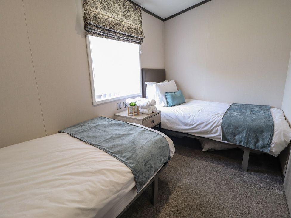 A bedroom with two single beds and a nightstand at Heather William Lodge near Woodhall Spa