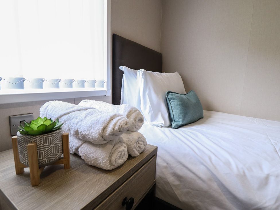 A bedroom with a bed and towels on a nightstand at Heather William Lodge near Woodhall Spa