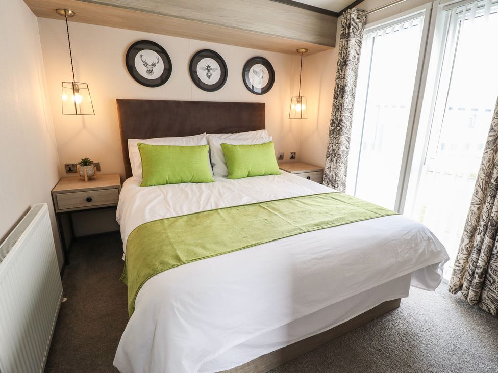A bedroom with a double bed and nightstand at Heather William Lodge near Woodhall Spa