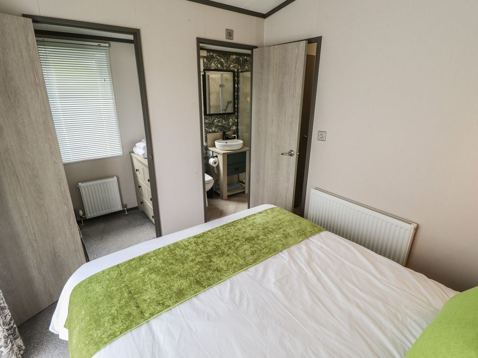 A bedroom with a door leading to a bathroom at Heather William Lodge near Woodhall Spa