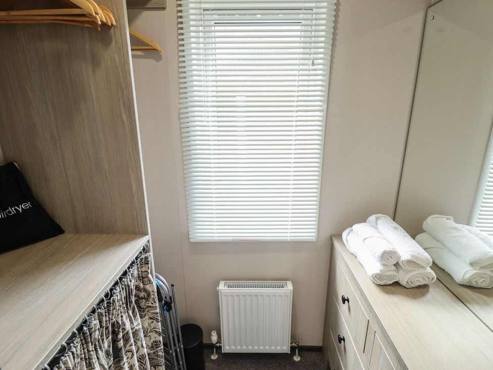 A bedroom with a wardrobe and towels at Heather William Lodge near Woodhall Spa