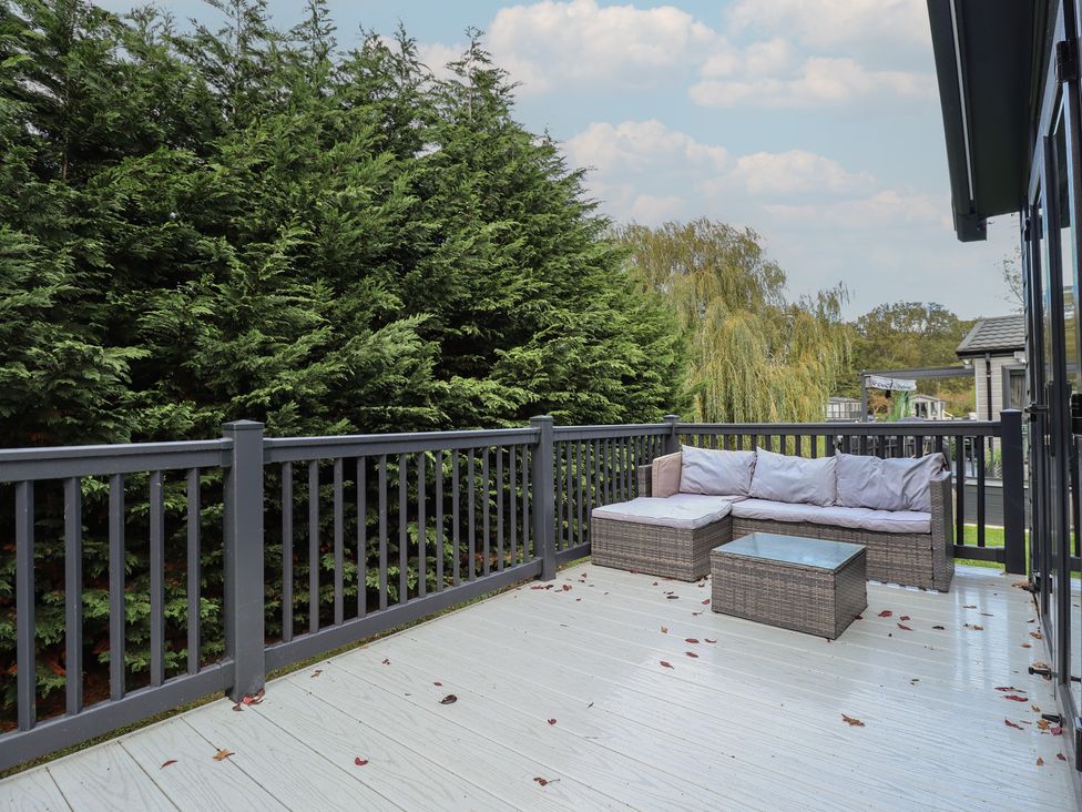 A deck area with a couch and a coffee table at Heather William Lodge near Woodhall Spa
