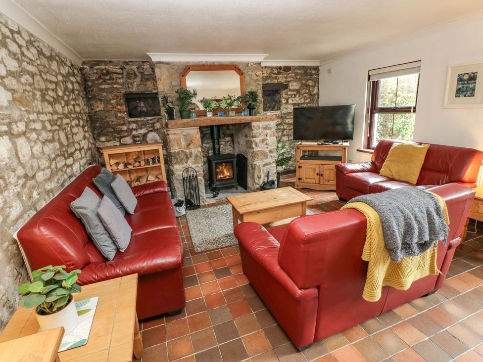 A living room with sofa and fireplace at The Coach House in Broad Haven