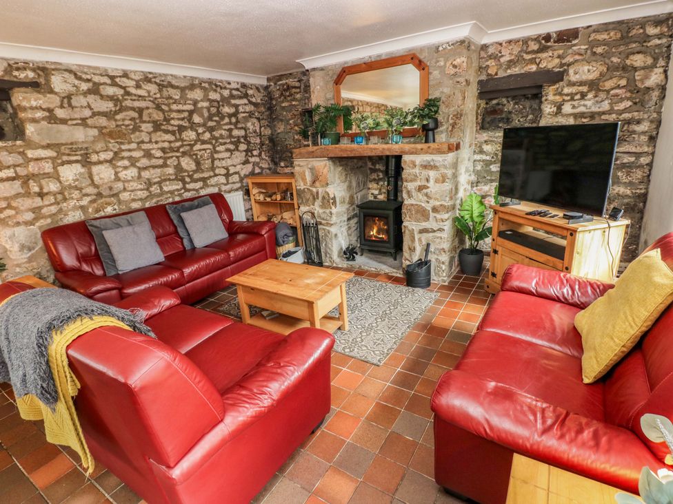 A living room with a fireplace and sofa at The Coach House in Broad Haven