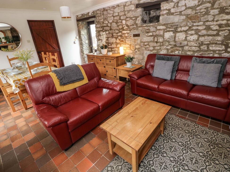 A living room with a red sofa and a wooden coffee table at The Coach House in Broad Haven