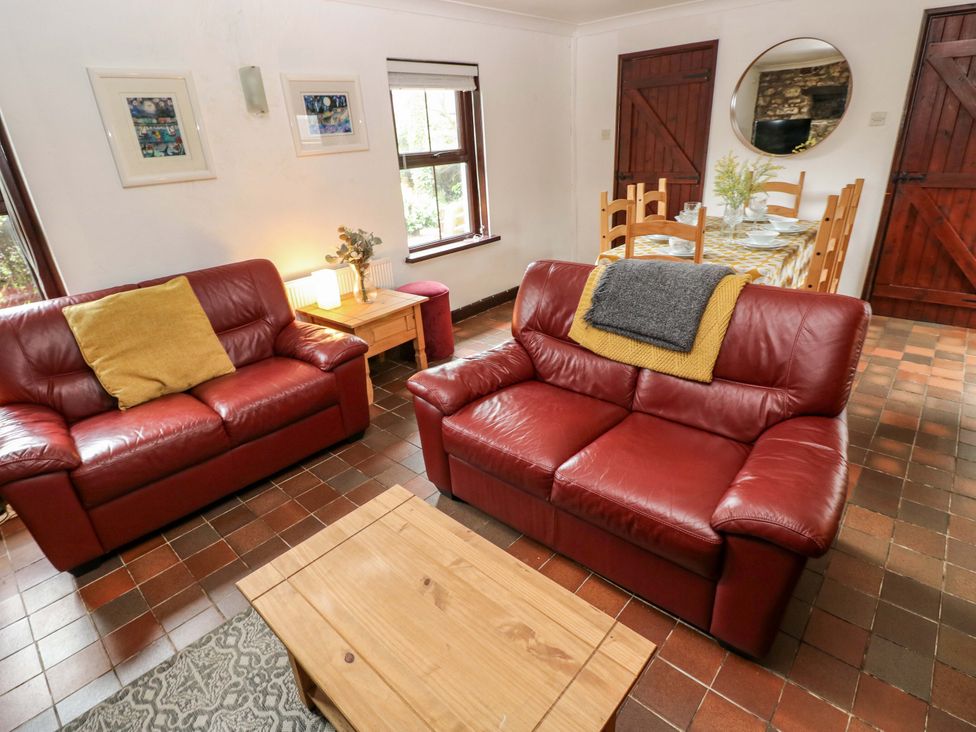 A living room with two sofas and a dining table at The Coach House in Broad Haven