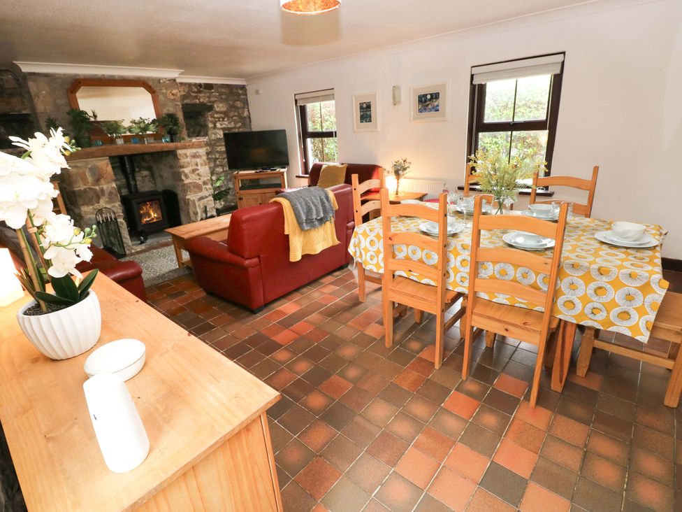 A living room with a dining area and fireplace at The Coach House in Broad Haven