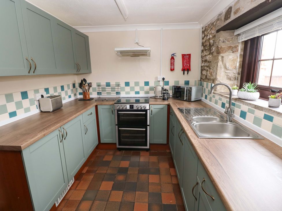 A kitchen with cabinets, counter, sink, stove and appliances at The Coach House Broad Haven