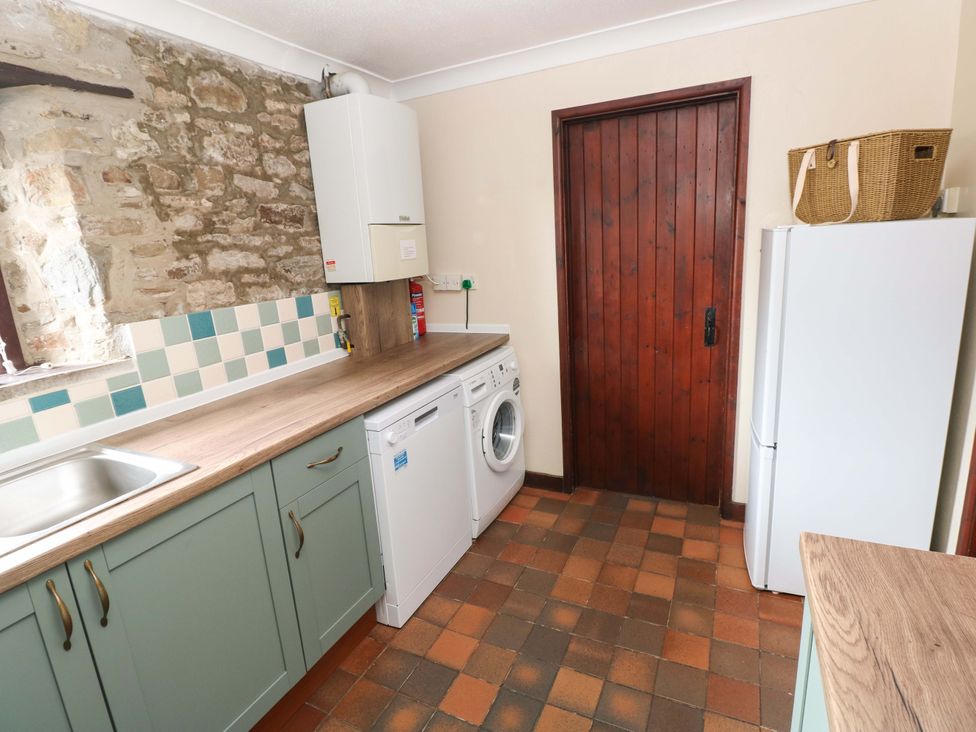 A kitchen with a washing machine and refrigerator at The Coach House Broad Haven