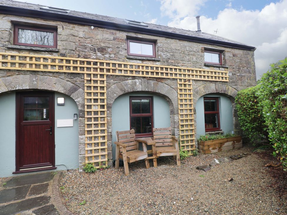 An outdoor area with a bench and gravel at The Coach House in Broad Haven