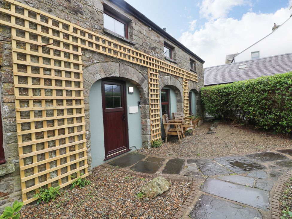 An outdoor area with a stone wall and wooden trellis at The Coach House in Broad Haven