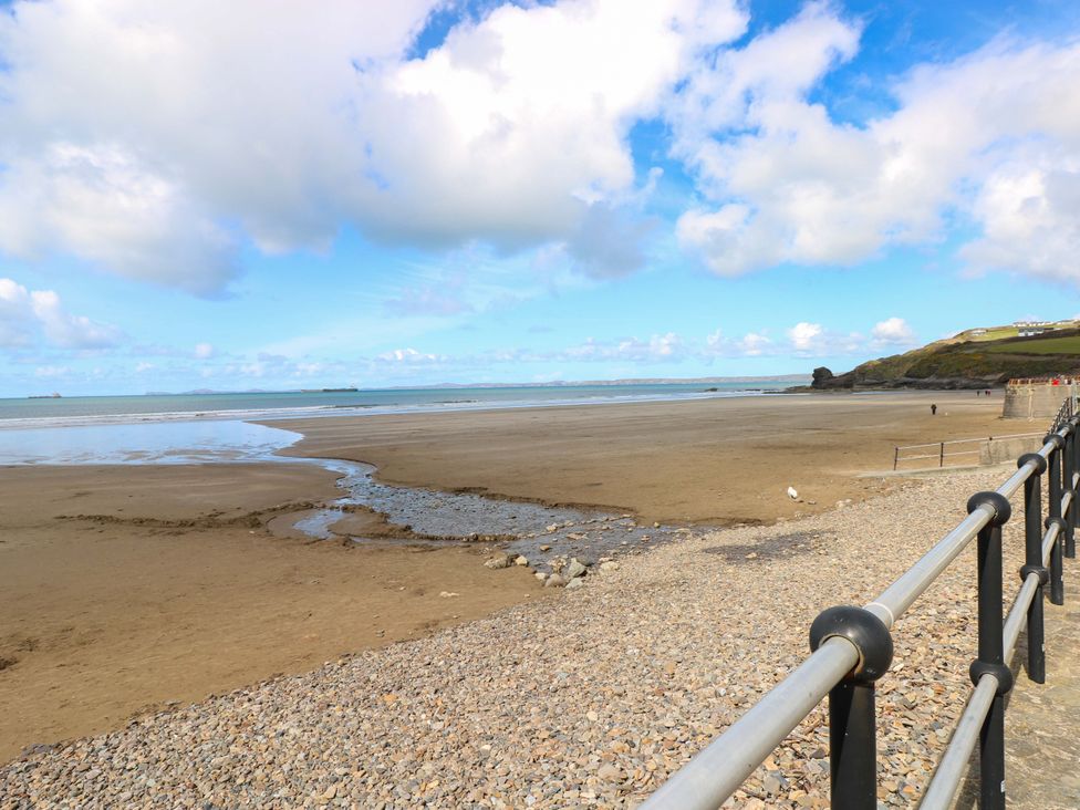 A beach with sand, water, and a fence at The Coach House in Broad Haven