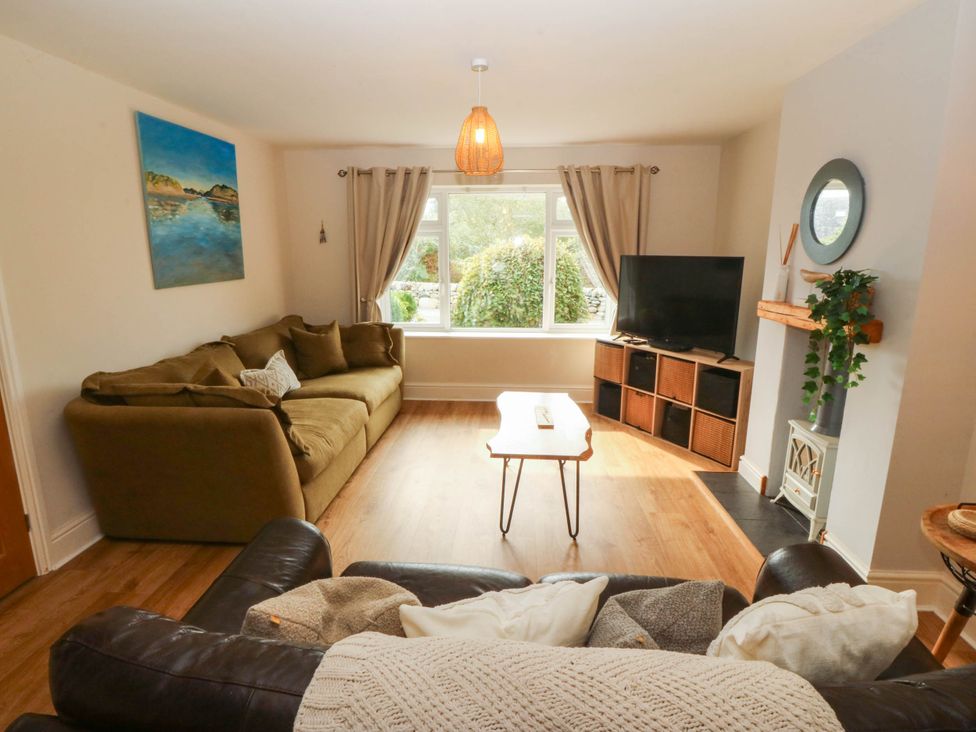 A living room with a sofa, television, and table at Ty Ni in Dyffryn Ardudwy