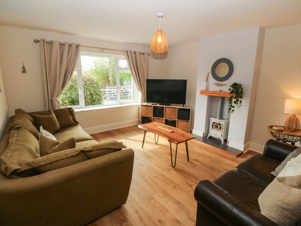 A living room with a sofa, television, and coffee table at Ty Ni in Dyffryn Ardudwy