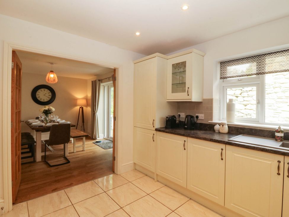 A kitchen with cabinets, coffee maker, and a doorway to the dining area at Ty Ni Dyffryn Ardudwy
