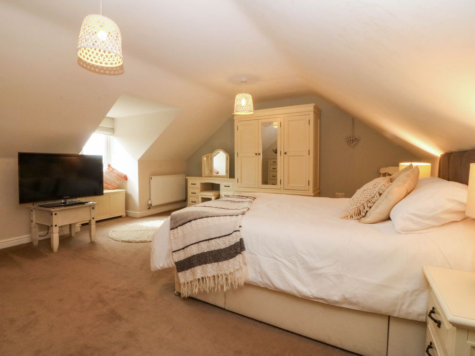 A bedroom with a bed and a television at Ty Ni in Dyffryn Ardudwy