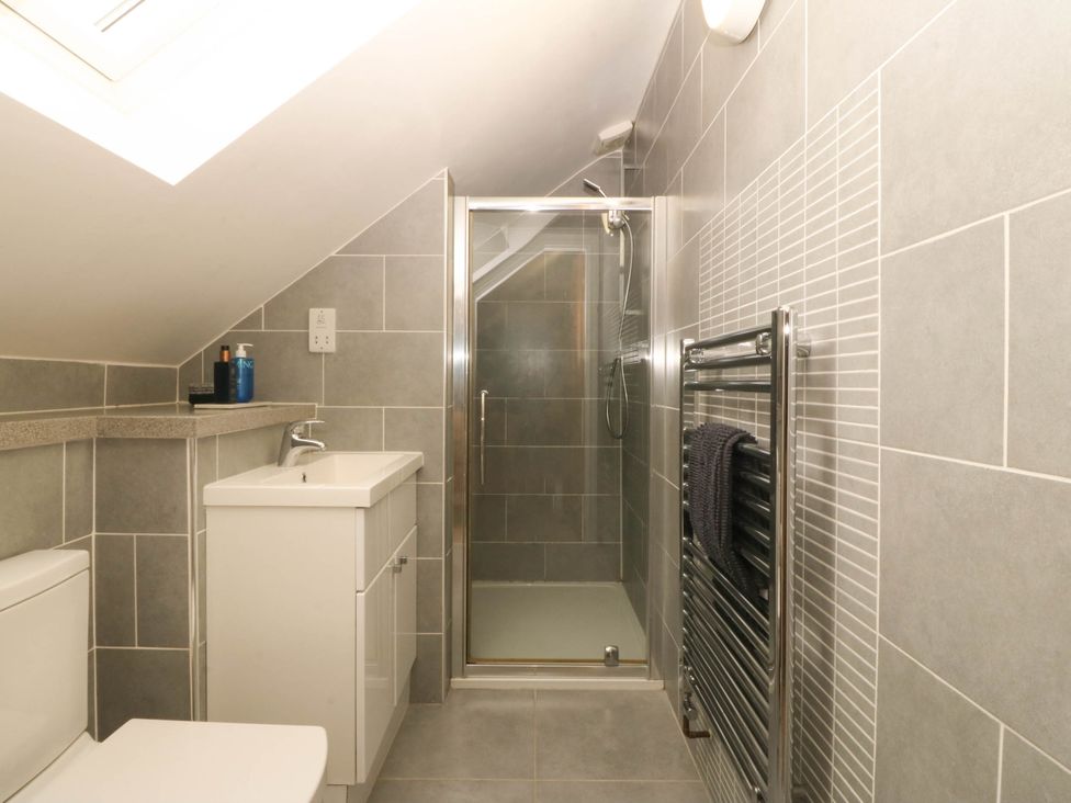 A bathroom with a toilet, sink, shower, and towel radiator at Ty Ni Dyffryn Ardudwy