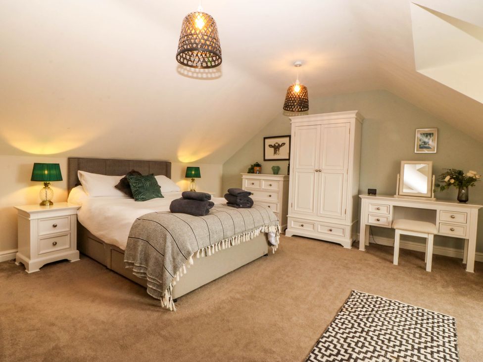 A bedroom with a bed, wardrobe, nightstands, and a desk at Ty Ni Dyffryn Ardudwy