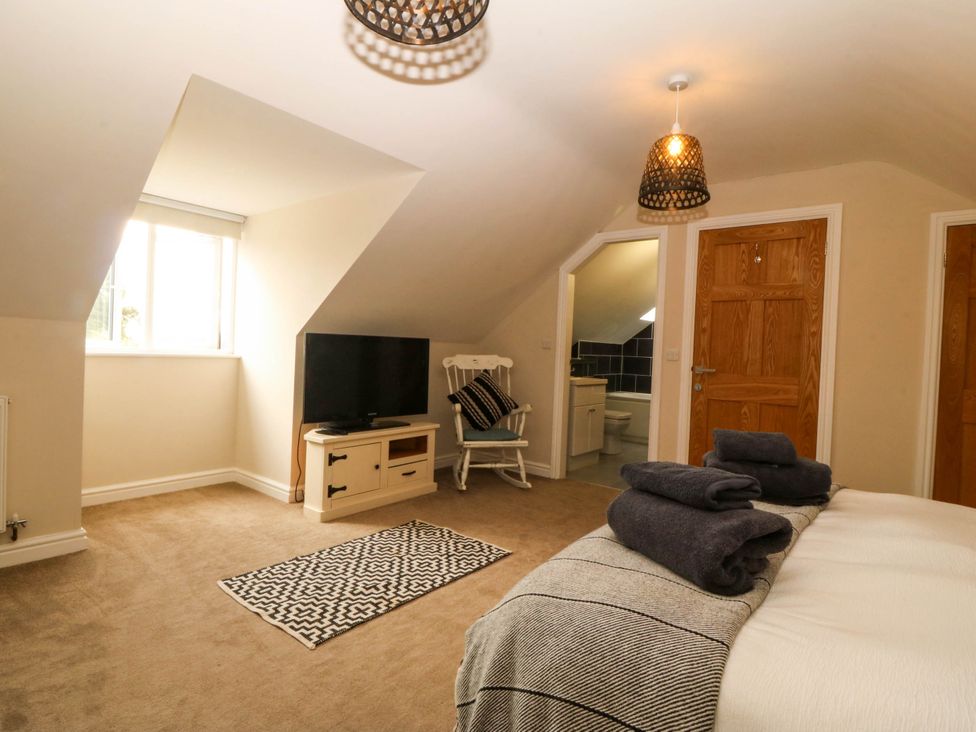A bedroom with a bed, television, and towels at Ty Ni Dyffryn Ardudwy