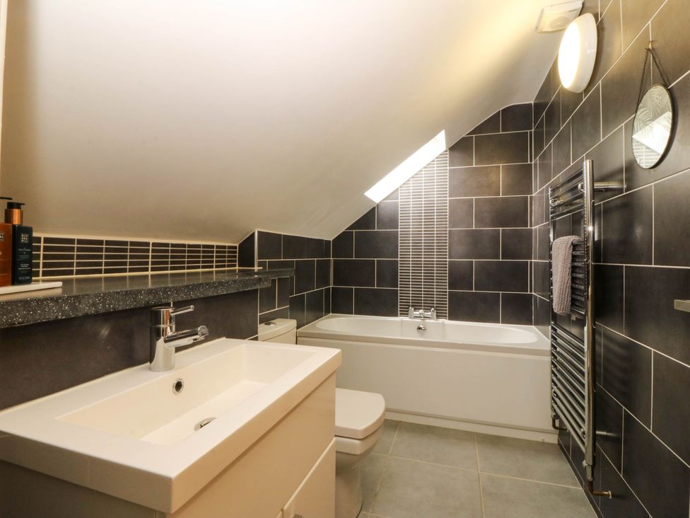 A bathroom with a sink, toilet, bathtub, and towel radiator at Ty Ni in Dyffryn Ardudwy