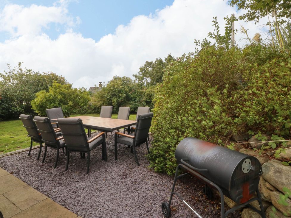 A garden with a table and chairs, a grill, and plants at Ty Ni in Dyffryn Ardudwy